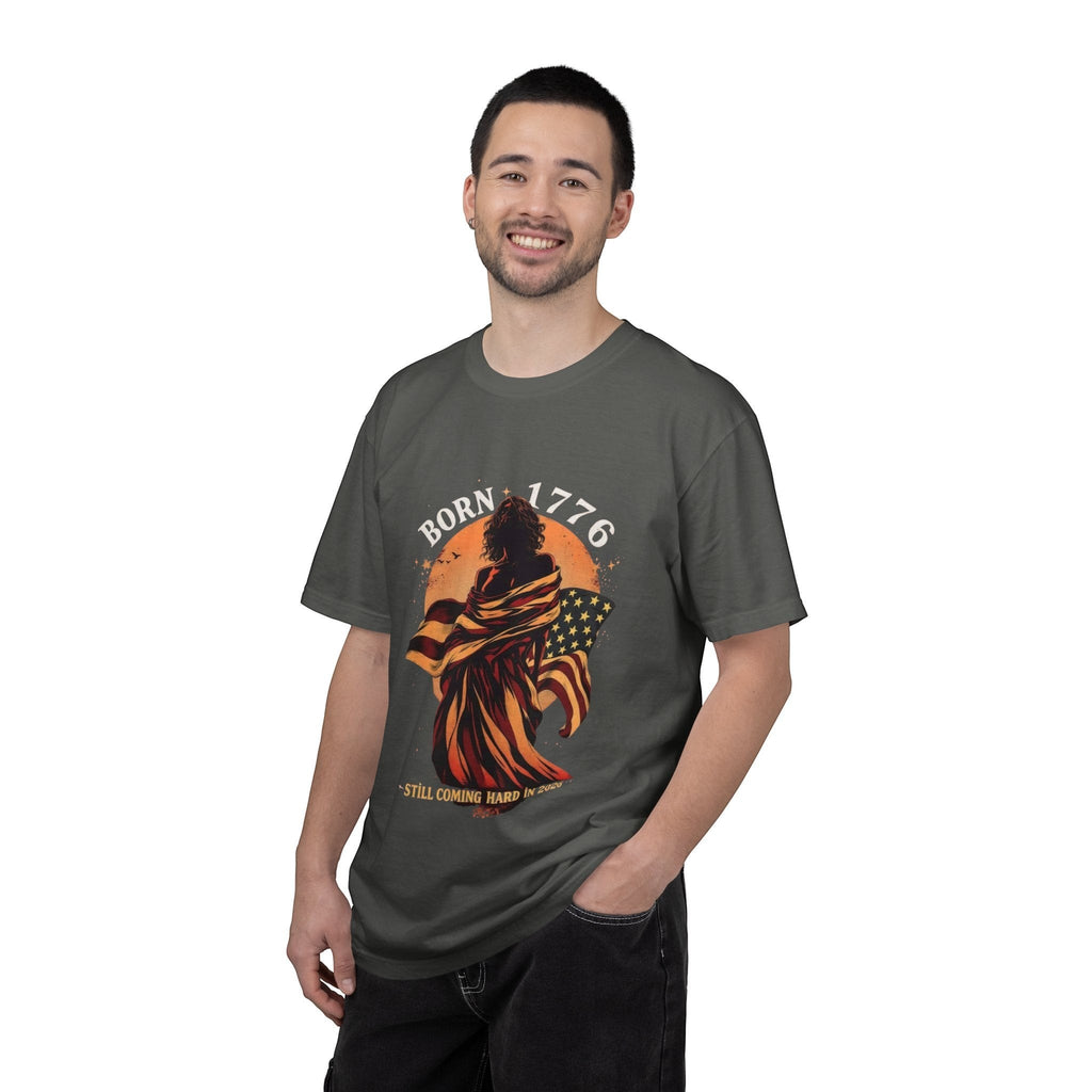 Naughty250 charcoal grey cotton t-shirt with a graphic of a figure wrapped in the American flag and the text "Born 1776 – Still Coming Hard in 2026".