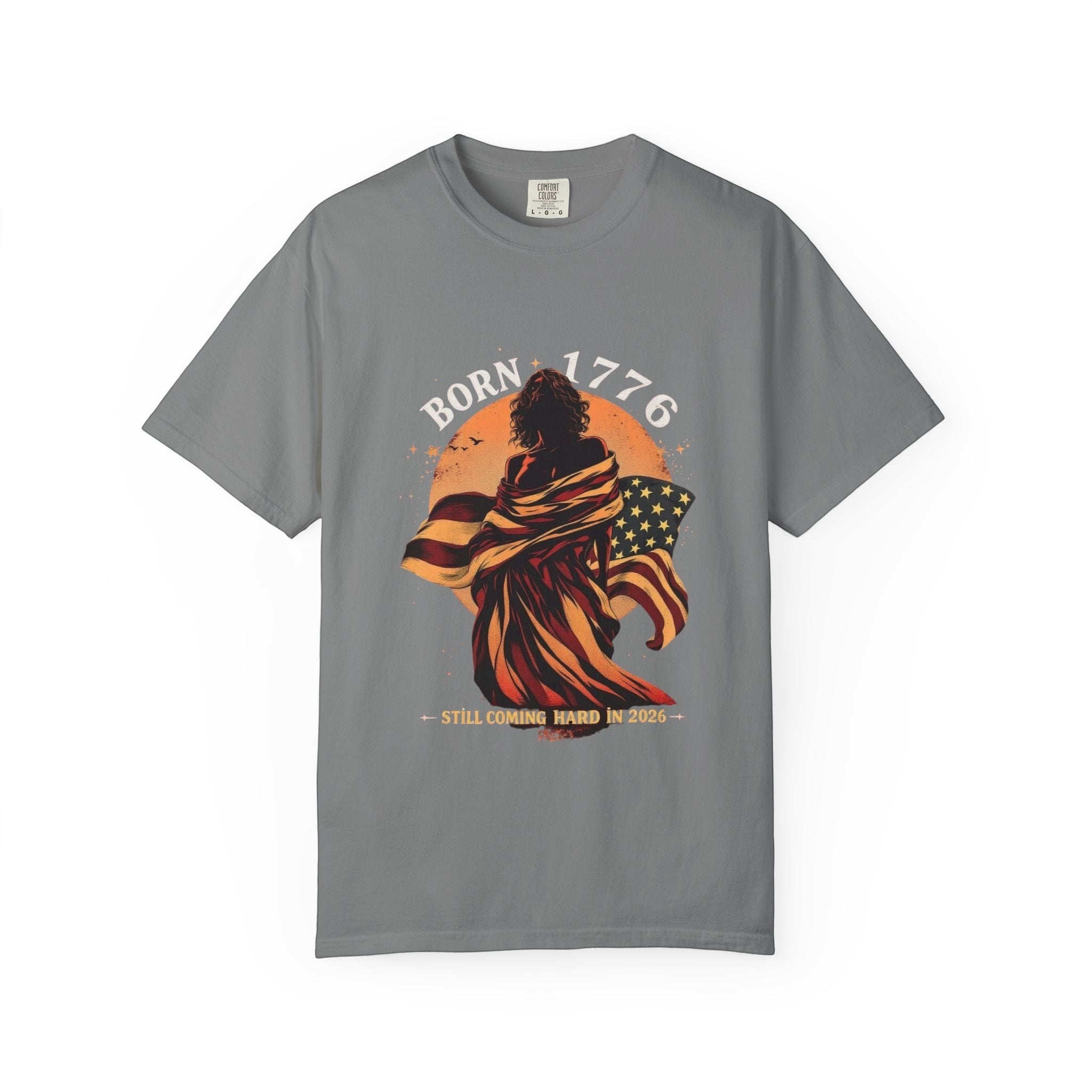 Naughty250 grey cotton t-shirt with a graphic of a figure wrapped in the American flag, text "Born 1776" and "Still Coming Hard in 2026".