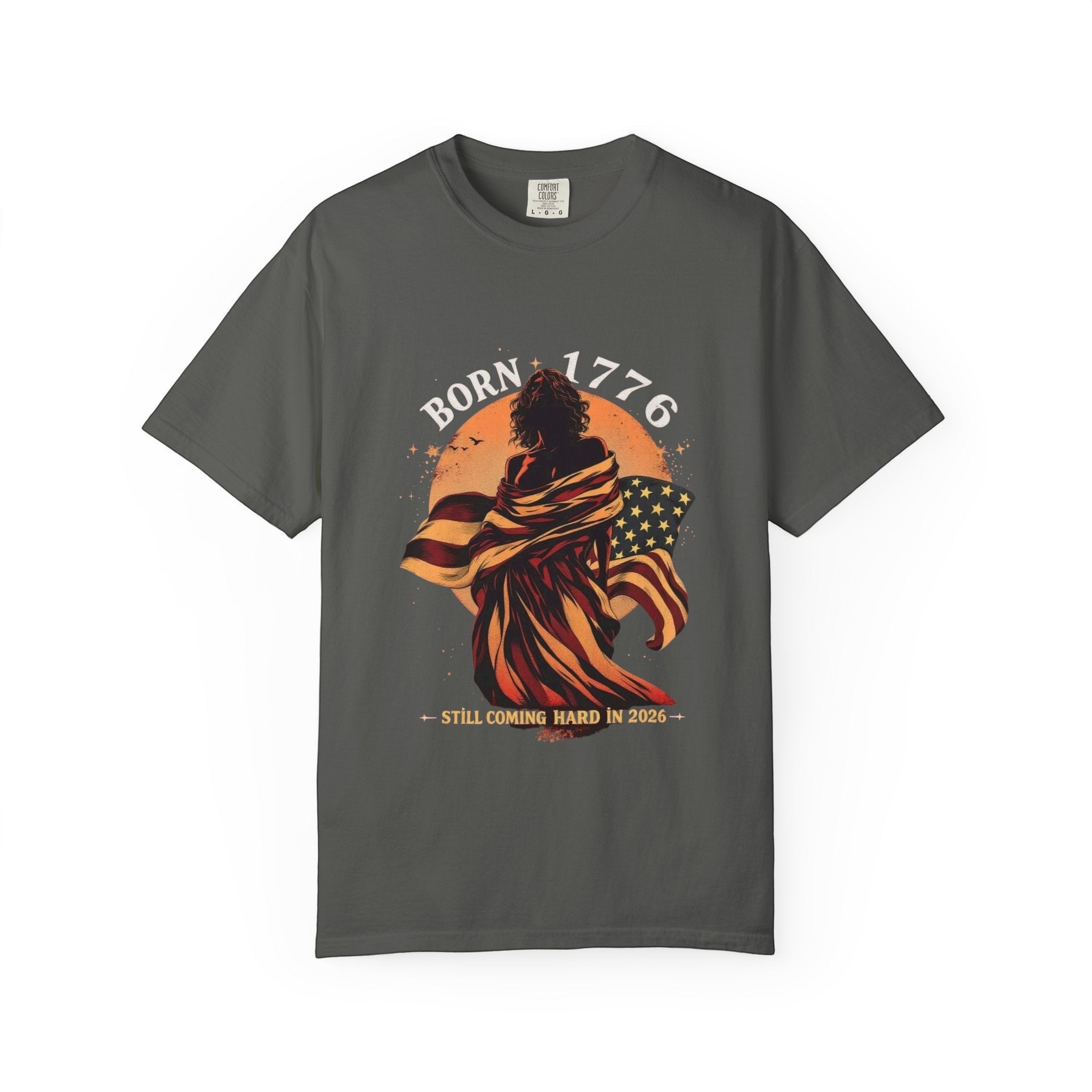 Naughty250 charcoal grey cotton t-shirt with a graphic of a figure wrapped in the American flag, text "Born 1776" and "Still Coming Hard in 2026".