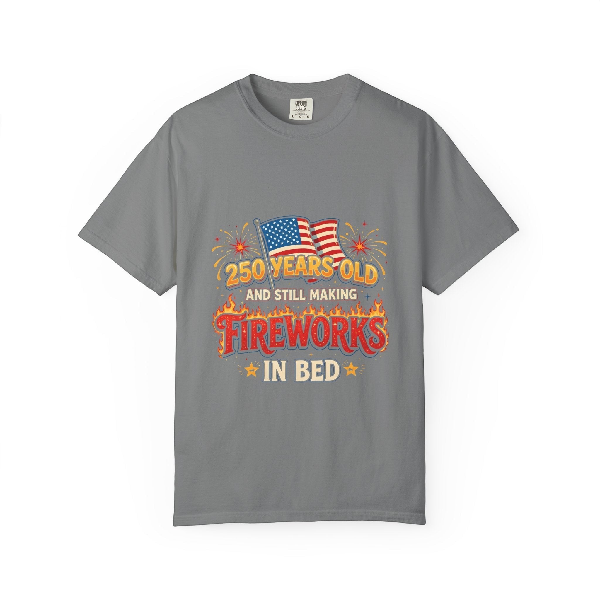 Naughty250 grey heavyweight cotton tee with retro fireworks graphic, American flags, and "250 Years Old & Still Making Fireworks In Bed" text.