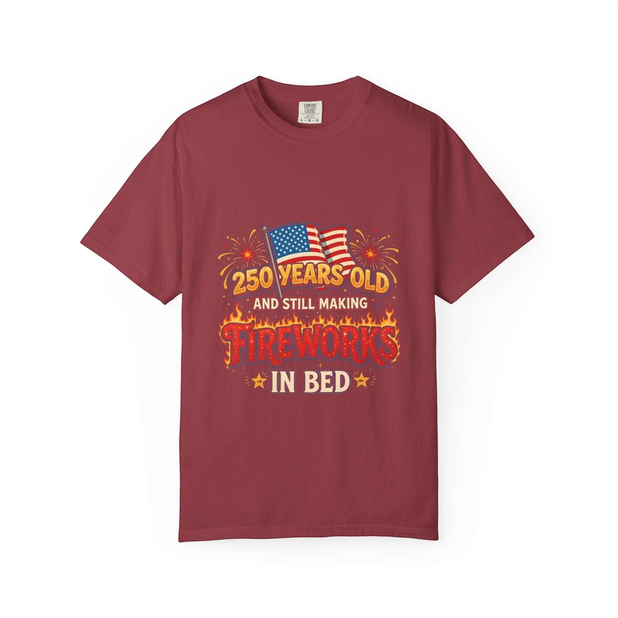 Naughty250 maroon heavyweight cotton tee with retro fireworks graphic, American flags, and "250 Years Old & Still Making Fireworks In Bed" text.