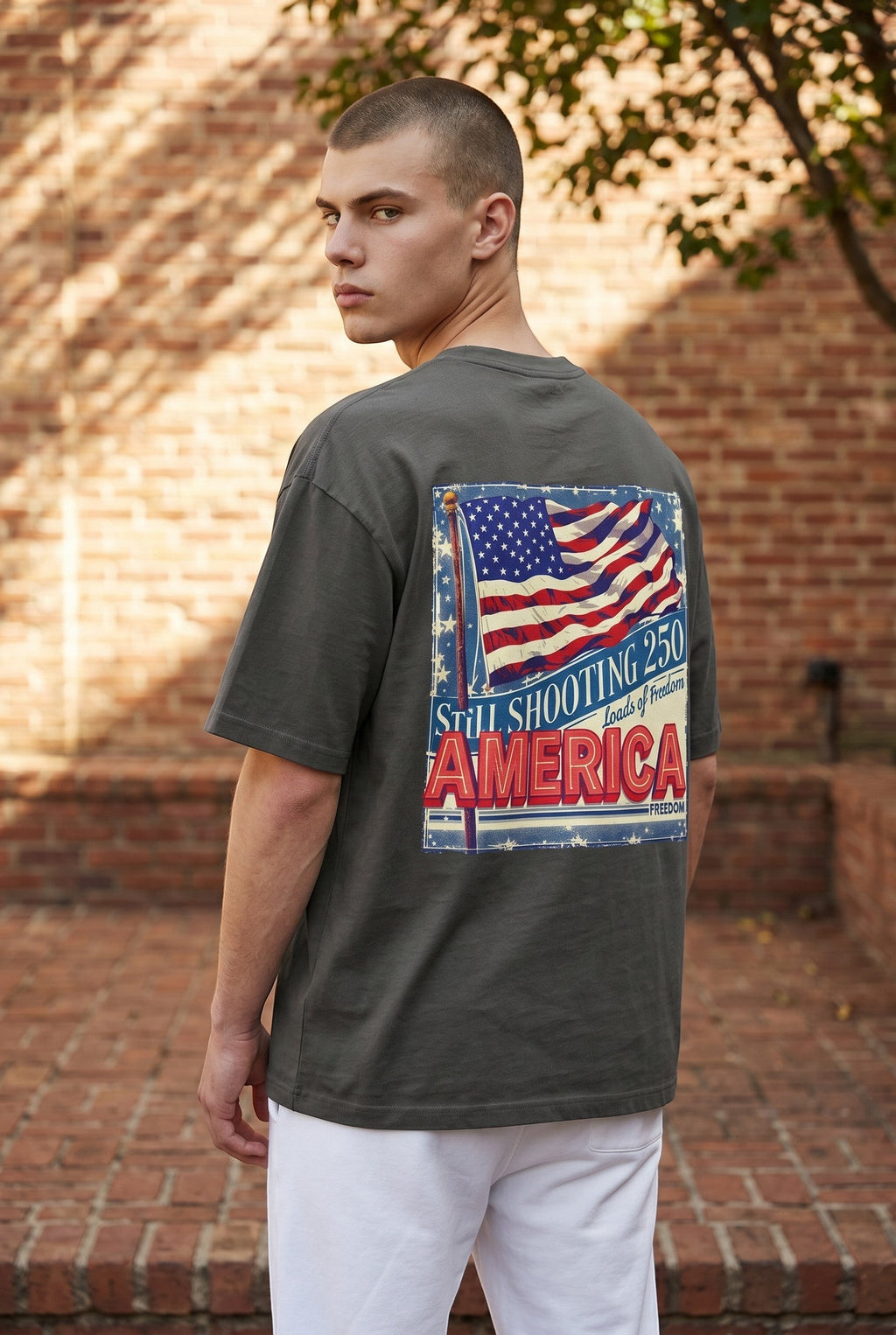 Naughty250 dark grey heavyweight cotton t-shirt with a retro American flag graphic and "Still Shooting 250 Loads of Freedom America" text on the back.